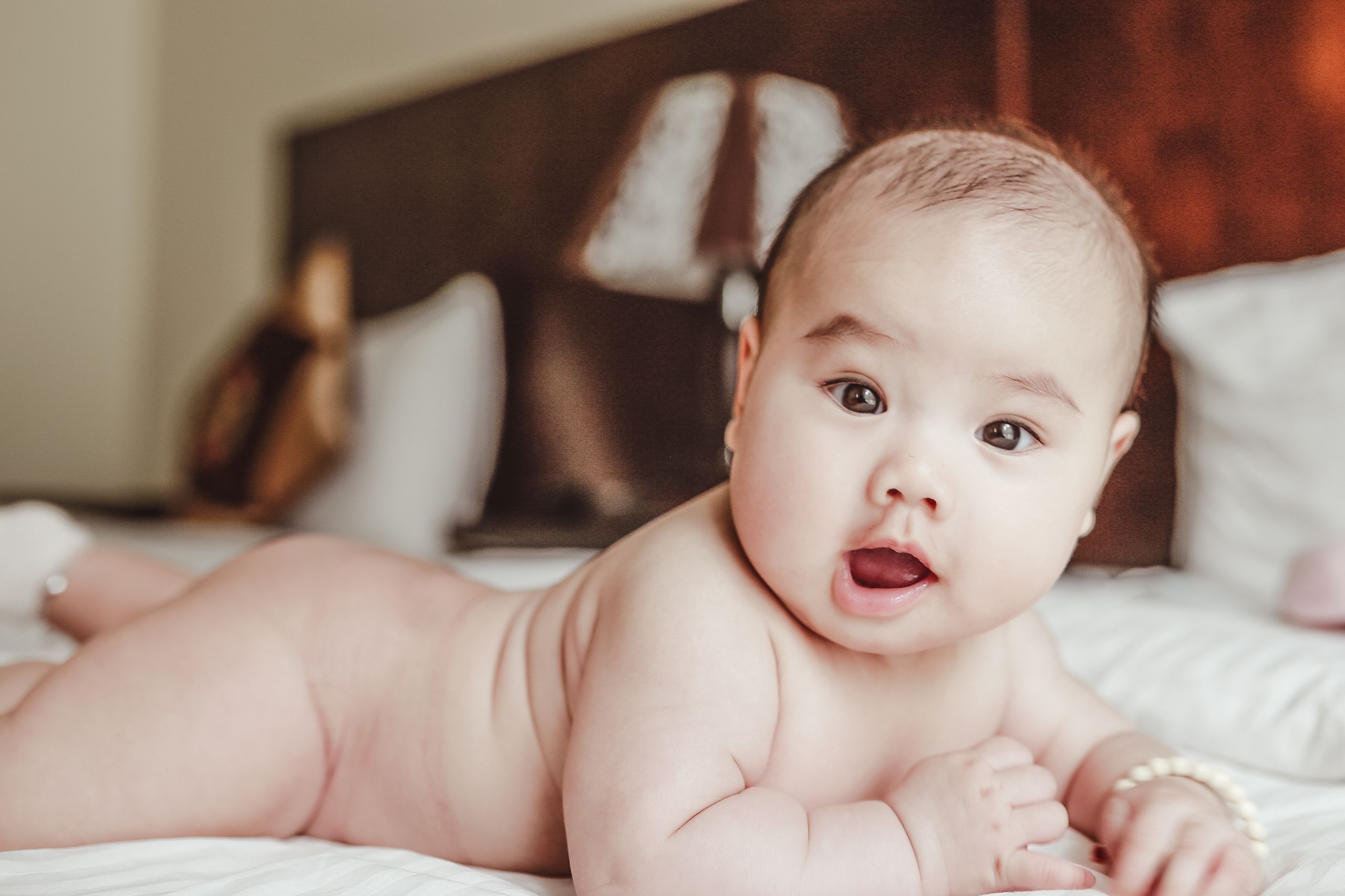 baby lying on a bed, focusing curiously