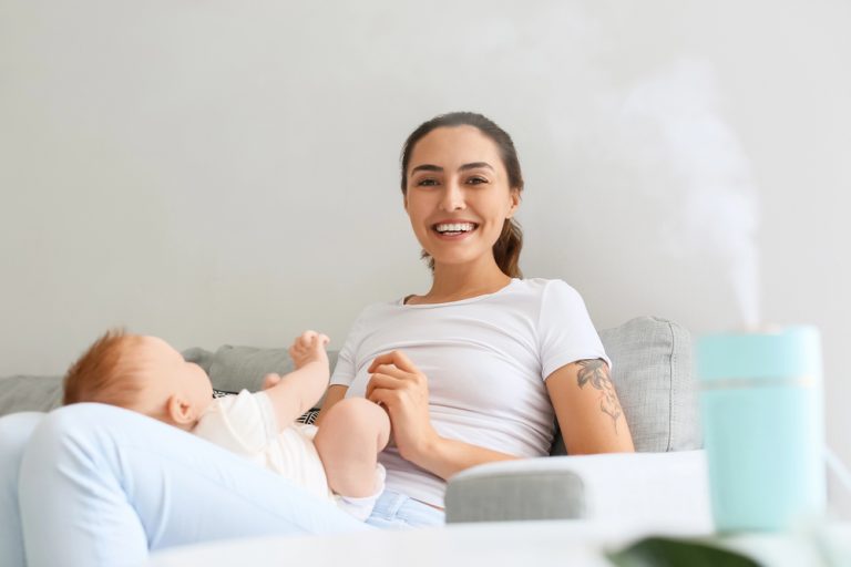 mom and baby sitting by humidifier